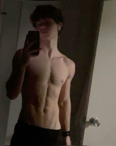 a shirtless young man taking a selfie in the mirror with his cell phone