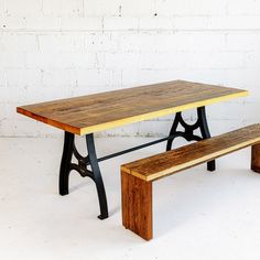 a wooden table with two benches next to it on a white wall background in front of a brick wall