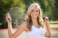 a woman holding a tennis racquet in her right hand and smiling at the camera