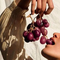 a person holding grapes up to their face