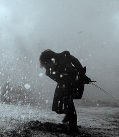 a person walking in the snow with an umbrella on their head and one arm extended