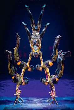 a group of people standing on stilts in the middle of a dance pose with their hands up