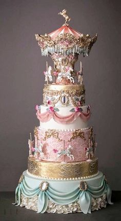 a three tiered cake with pink, blue and gold decorations