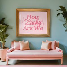 a pink couch sitting in front of a painting on the wall next to potted plants