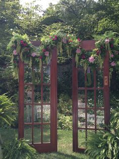 two wooden mirrors with flowers on them in the grass near trees and bushes, along with other plants