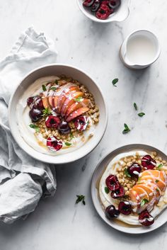 two bowls filled with oatmeal and fruit on top of a white table