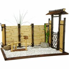 a small bamboo fence with rocks and gravel in front of it on a white background