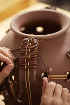 a person is working on a vase that has been made from wood and leathers