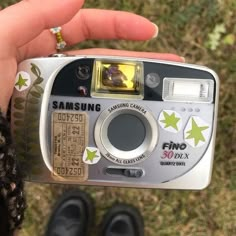 a person holding up a camera with stickers on it's front and side