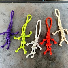 four different colored string toys sitting on top of a cement floor next to each other