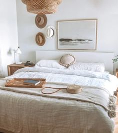 a bed with white linens and hats on the headboard, hanging above it