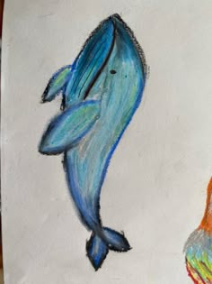 a drawing of a dolphin and a fish on a piece of paper with colored crayons