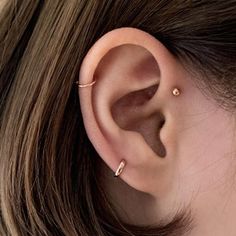 a woman's ear is shown with two piercings on the end of it