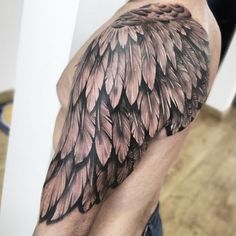 a man's arm with an angel wing tattoo on it, which is black and grey