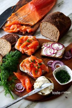 an assortment of breads, fish and vegetables on a cutting board