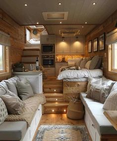 a living area with couches, kitchen and stairs leading up to the loft bed