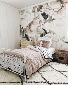 a white bed sitting in a bedroom next to a wall with flowers painted on it