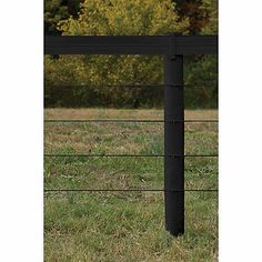 a black metal fence in the middle of a grassy field