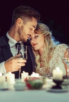 a man and woman sitting at a table with wine glasses