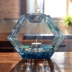 a glass candle holder sitting on top of a wooden table