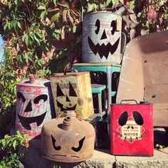 an assortment of painted metal buckets sitting on top of a cement slab next to a tree