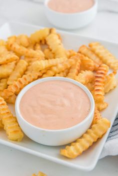 a white plate topped with cheesy fries and dipping sauce on top of it