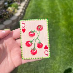 a hand holding up a playing card with tomatoes on it