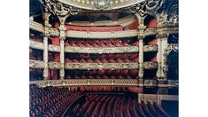 an ornately decorated auditorium with red seats and a clock on the top of it