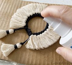 someone is painting the tassels on a piece of cardboard with white and black paint