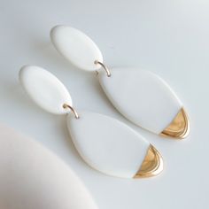 Modern white earrings from our collection "Flow". Handmade from porcelain, painted with stunning 24k gold and finished with hypoallergenic sterling silver studs. Earrings are sent in a gift box and are ready to ship. SIZE AND MATERIAL Measures: 56 x 20mm (2.2 x 0.78 in) Lightweight: 10g a pair Sterling silver studs - hypoallergenic Porcelain covered in a gloss glaze from one side and painted with gold HANDMADE It takes a long time to achieve the final result. Each porcelain jewelry piece is fini Minimalist White Jewelry For Pierced Ears, Minimalist White Jewelry With Matching Earrings, Modern White Jewelry For Gifts, White Teardrop Earrings As Gift, Minimalist White Drop Earrings, White Hypoallergenic Earrings For Everyday, Hypoallergenic White Earrings For Everyday, Porcelain Earrings, Keramik Design