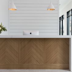 an empty reception area with white walls and wood paneling on the front desk, along with two hanging lights