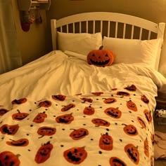 a white bed topped with pillows covered in pumpkins