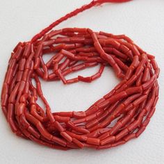 a long red necklace on a white surface