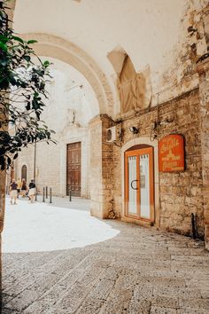 an archway leading to a building with a sign on the door and people walking by