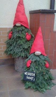 two gnomes made out of christmas trees sitting next to each other on the ground