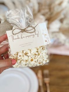 a person holding a bag of popcorn in front of a table with plates and napkins