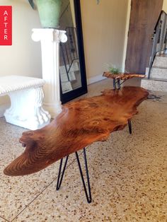 a wooden table sitting on top of a floor next to a white vase and mirror