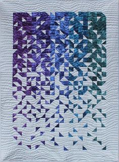 a quilt made with blue and purple triangles on the front, in two rows that have been