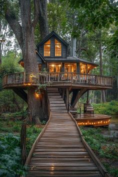 a tree house in the woods with stairs leading up to it and lights hanging from the roof