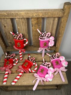 some candy canes and cups are on a wooden bench with pink bows around them