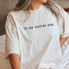 a woman wearing a white t - shirt with the words in my aurite era printed on it