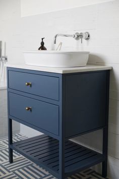 a white sink sitting next to a blue cabinet in a bathroom under a faucet