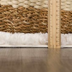 a wooden ruler sitting on top of a floor next to a white and brown rug