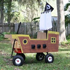 a homemade pirate ship made out of cardboard on the grass in front of a tree