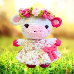 a small crocheted sheep with flowers on its head is standing in the grass