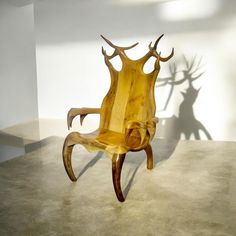 a wooden chair sitting on top of a floor next to a shadow of a deer