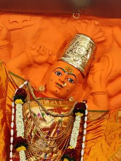 an orange statue with a gold crown on it's head and other decorations around its neck