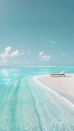 a bench sitting on top of a sandy beach next to the ocean under a blue sky