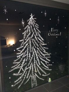 a window with a christmas tree drawn on it's glass and snowflakes