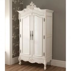 an ornate white armoire stands in the corner of a room with wood flooring